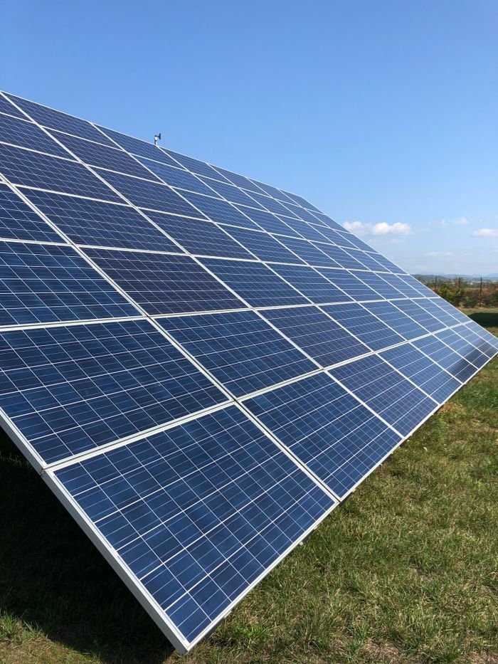 about-us-01 Solar panels in a green field on a sunny day, showcasing renewable energy in Tortona, Italy.