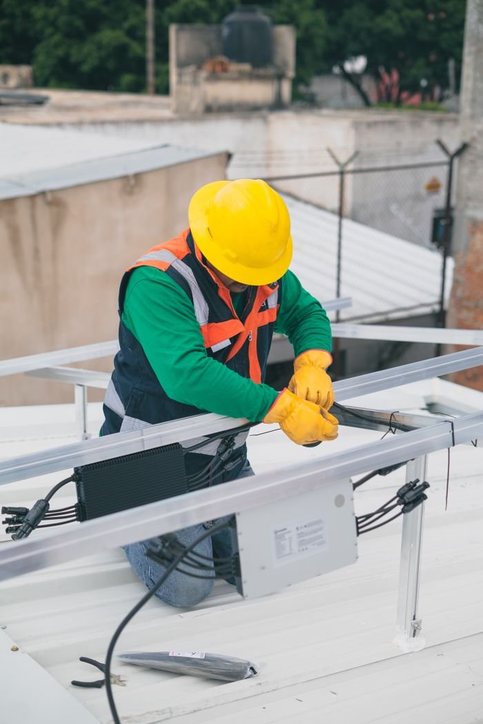 services-04 Electrician with PPE working on rooftop solar panel installation, focusing on safety.